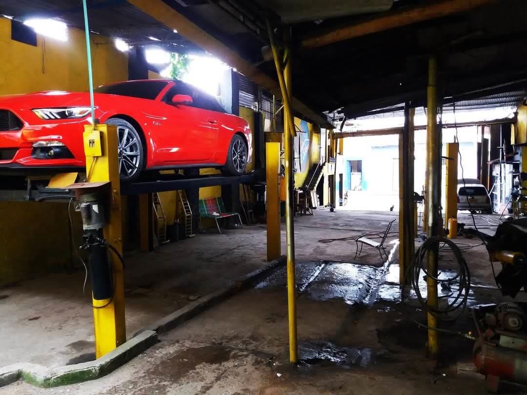 Mustang rojo en el elevador del taller para revisar el exosto