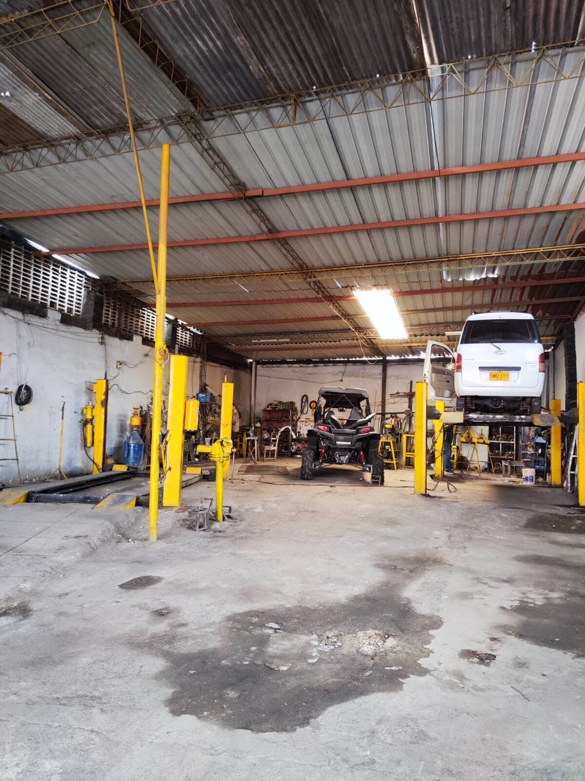 Interior del Taller el Silencioso en Bucaramanga, con vehículos en los elevadores